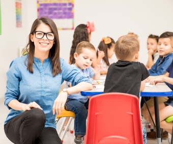 Portrait of a gorgeous Hispanic preschool teacher loving her job and having fun with her pupils