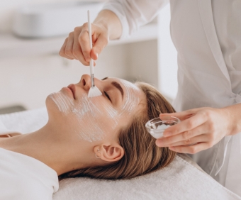 Cosmetologist doing face treatment and applying face mask