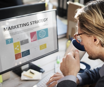 Closeup of caucasian man drinking coffee with computer screen showing marketing strategy